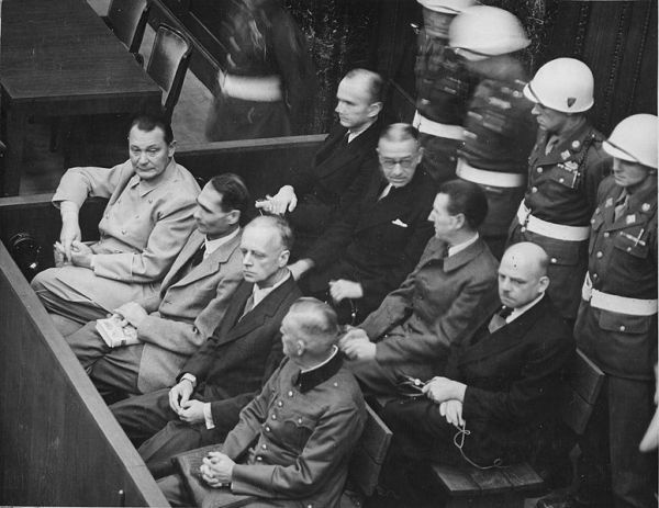 Trybunał Wojskowy w Norymberdze, ława oskarżonych. Od lewej w pierwszym rzędzie: Göring, Hess, Ribbentrop, Keitel, w drugim rzędzie: Dönitz, Raeder, Schirach, Sauckel (domena publiczna)